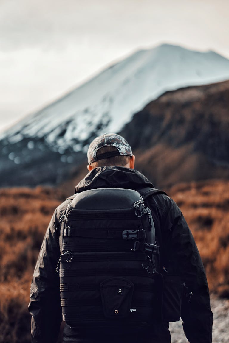 Back view of a hiker exploring mountainous terrain in daylight.